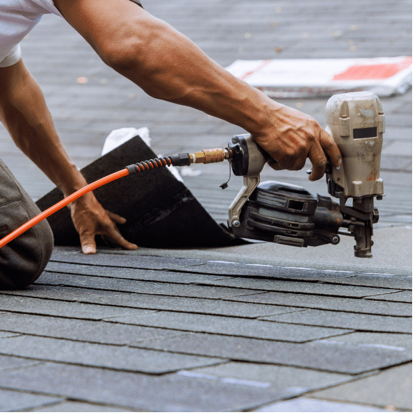 A person uses a pneumatic nail gun to secure asphalt shingles on a roof during an Emergency Roof Leak Repair in Salt Lake City, ensuring a quick response and effective roofing installation or repair.