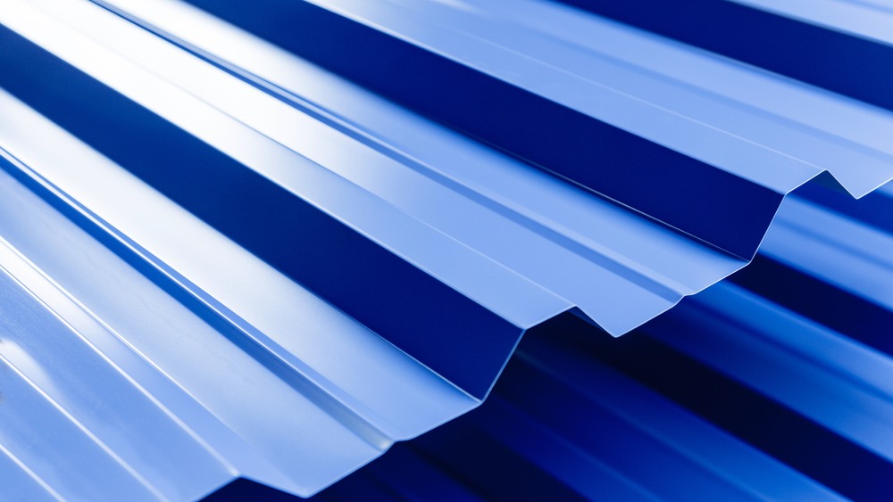 Close-up view of overlapping blue corrugated metal sheets with a shiny, reflective surface.